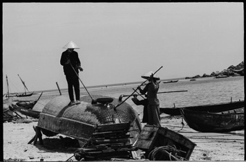 The bottom of many boats are constructed of woven reeds, with wood plank topsides. Here men pain the reed bottom with tar.